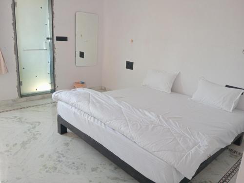 a white bed in a room with a window at Bagol Niwas in Udaipur