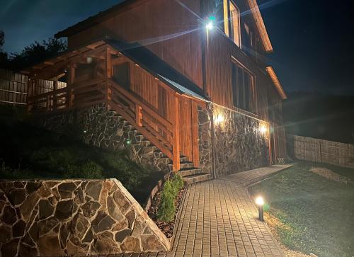 a house with lights on the side of it at night at Садиба Трембіта з сауною та чаном in Rakhiv