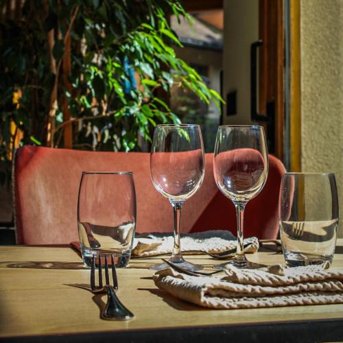 four wine glasses sitting on a wooden table at Le Bois Dormant-Hôtel Restaurant & Spa Logis Hôtel in Champagnole