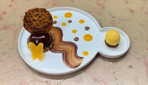 a white plate with a cookie and a dessert on it at Le Bois Dormant-Hôtel Restaurant & Spa Logis Hôtel in Champagnole