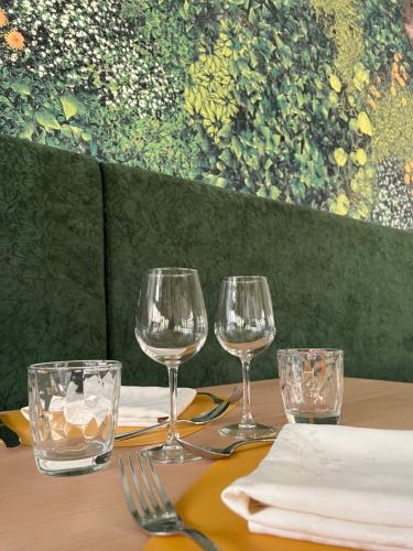 a table with three wine glasses on a table at Le Bois Dormant-Hôtel Restaurant & Spa Logis Hôtel in Champagnole