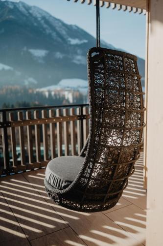 a hanging chair on a balcony with a view at Hotel Berghof - St Johann in Salzburg in Sankt Johann im Pongau