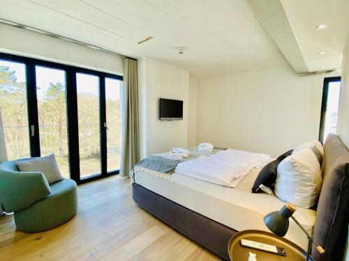a bedroom with a bed and a chair and windows at Ferienwohnung Penthouse 17 im Haus Düne 7 Prora in Binz
