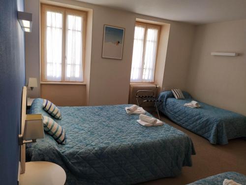 a hotel room with two beds and two windows at Hôtel restaurant Notre Dame in Orcival