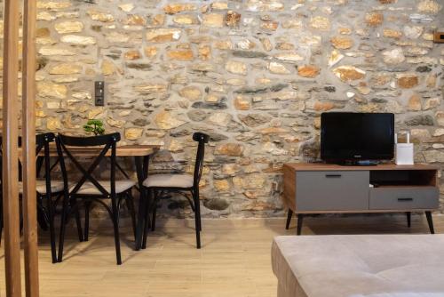 a room with a table and chairs and a stone wall at The Lake House Angeliki in Kanália