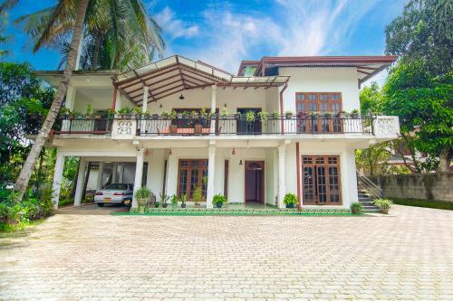 a white house with a balcony and a driveway at ALP Tourist Guest House in Ella