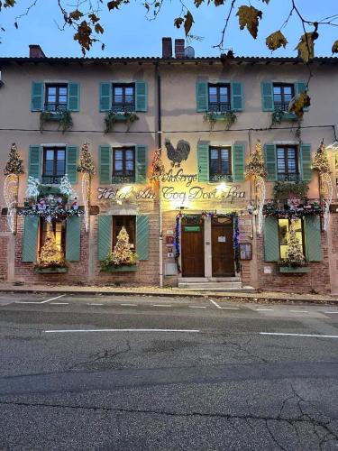 a building with green shutters and flowers on the windows at Hôtel Au Coq Dort Spa in Châtillon-sur-Chalaronne