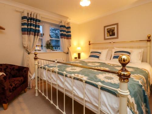 Un dormitorio con una cama y una silla y una ventana. en Woodside Cottage, en Skipton