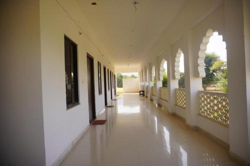 um corredor vazio de um edifício com paredes e janelas brancas em The Great Meva Palace Pushkar em Pushkar