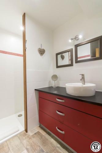 La salle de bains est pourvue d'une commode rouge et d'un lavabo. dans l'établissement Les gites du Canal du Midi - Gîte La Cordonnerie, à Renneville