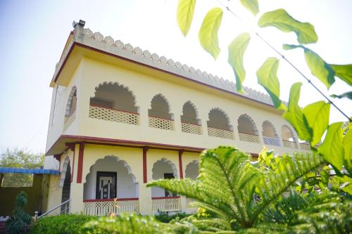 um edifício amarelo e branco com plantas verdes em frente em The Great Meva Palace Pushkar em Pushkar