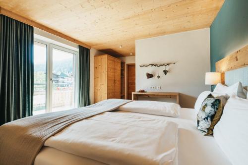 a bedroom with a large bed and a large window at Biohotel Rupertus in Leogang
