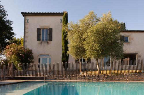 une maison et une piscine en face d'une clôture dans l'établissement Château Caillivet au cœur d'un vignoble Bio 14 personnes, à Mazères