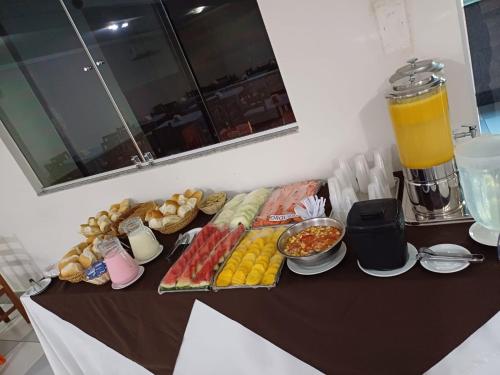 a table topped with food and a blender with orange juice at Hotel Absolar in Alagoinhas
