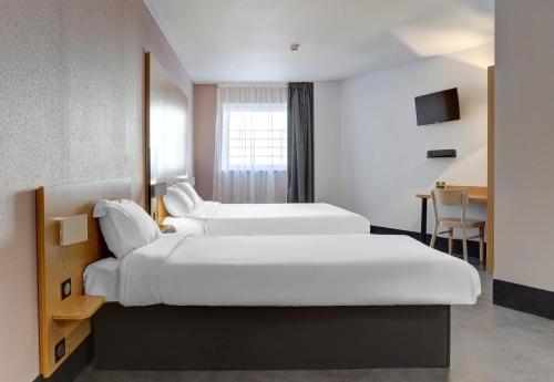 a hotel room with two beds and a table at B&B HOTEL Reims Centre Gare in Reims
