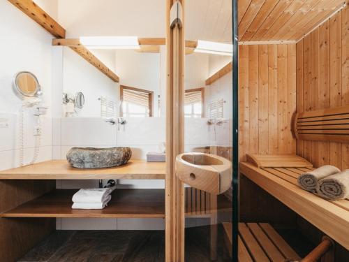 a bathroom with wood paneling and a shower and a sink at Biohotel Rupertus in Leogang