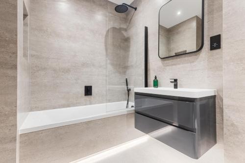 a bathroom with a sink and a mirror and a tub at Central 1Bed 1Bath 4ppl - 1min Russel Square Tube in London