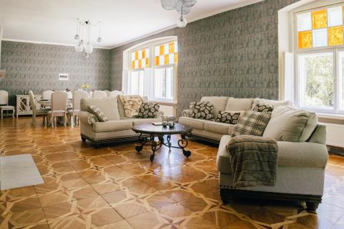 a living room with couches and a table and windows at Peetri mõis & spa in Turva