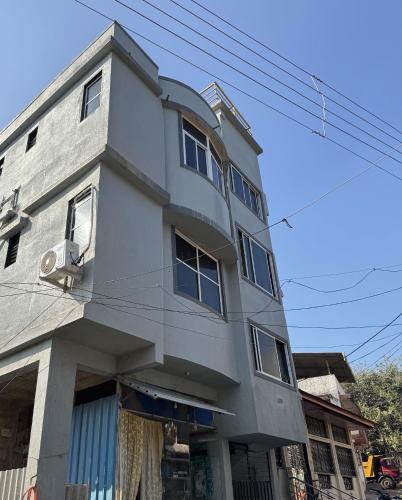 a tall gray building with windows on a street at soge holiday lodging in Srīvardhan