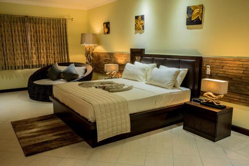 a bedroom with a large bed and a chair at Oasis Hotel Restaurant & Spa in Grand'Anse Praslin