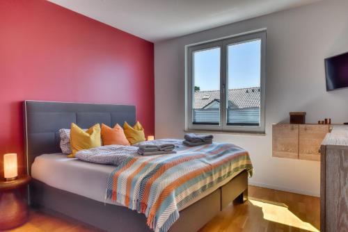una camera da letto con un letto con una parete rossa di Ferienwohnung Strandgold im Haus Seeblick Binz a Binz