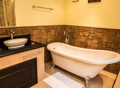 a bathroom with a bath tub and a sink at Oasis Hotel Restaurant & Spa in Grand'Anse Praslin
