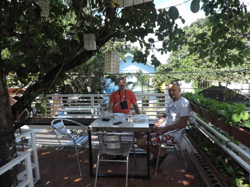 two men sitting at a table under a tree at Orange Mangrove Pension House by SMS Hospitality in Puerto Princesa City