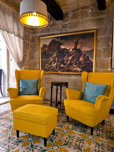 a living room with two chairs and a painting at The Valletta G-House in Valletta