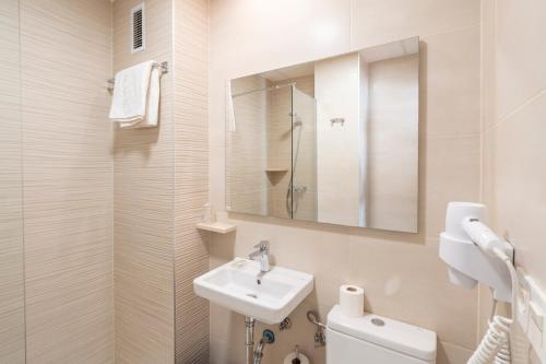 a white bathroom with a sink and a mirror at Hostal Pensimar in El Altet