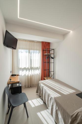 a bedroom with a bed and a desk and a television at Hostal Pensimar in El Altet