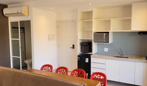 a kitchen with a table and some red chairs at Blend Coliving One - 2b in Ribeirão Preto