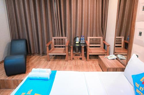a bedroom with a bed and two chairs and a table at Khách sạn Thế Kỷ Mới in Hanoi
