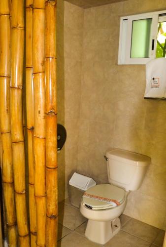 a bathroom with a toilet and a bamboo curtain at Bon Jesus Hotel in Costa Esmeralda