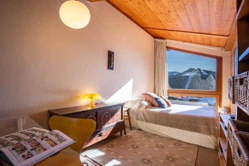 - une chambre avec un lit et une fenêtre offrant une vue sur la montagne dans l'établissement Chalet L'Epilobe, à Notre-Dame-de-Bellecombe