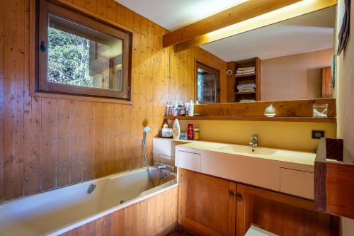 une salle de bain avec une baignoire et un lavabo dans l'établissement Chalet L'Epilobe, à Notre-Dame-de-Bellecombe