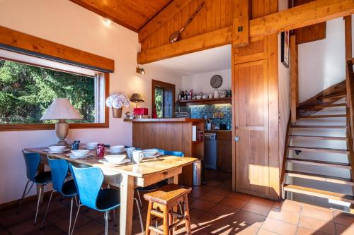 une salle à manger avec une table en bois et des chaises bleues dans l'établissement Chalet L'Epilobe, à Notre-Dame-de-Bellecombe