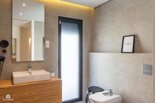 a bathroom with a sink and a mirror and a toilet at Varanda do Guincho - Classy Apt in Santa Cruz in Silveira