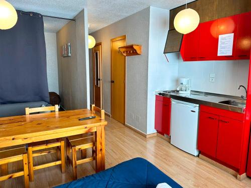 a kitchen with red cabinets and a wooden table at Apartamentos Solaris 3000 in Pas de la Casa