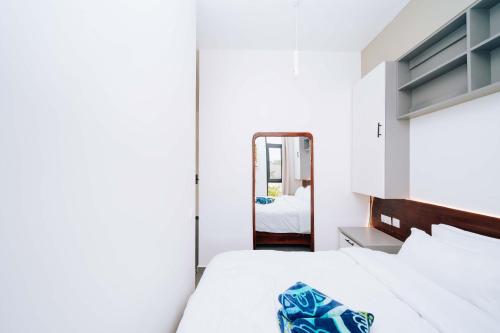 a white bedroom with a bed and a mirror at 1 BDR Garden Apartment at The Soul, Paje in Paje