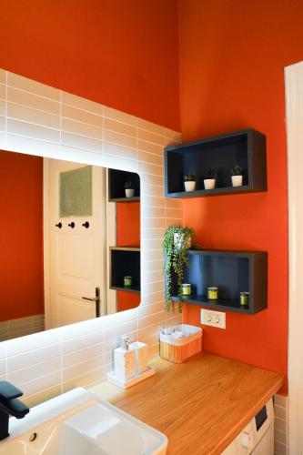 a bathroom with an orange wall with a sink and a mirror at Ami's Corner Lovely Family and Couple's home in Sibiu