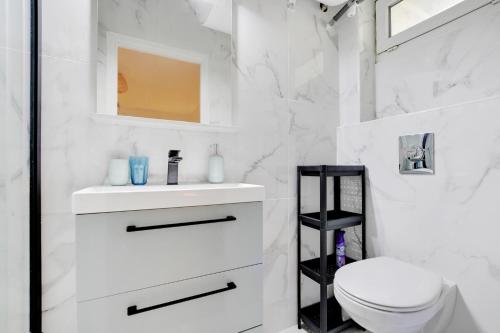 une salle de bain blanche avec des toilettes et un lavabo dans l'établissement Super Lilas cosy, aux Lilas