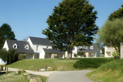 une grande maison blanche avec un arbre dans la cour dans l'établissement Maison dans résidence mer - piscine, à Loc-Maria-Plouzané
