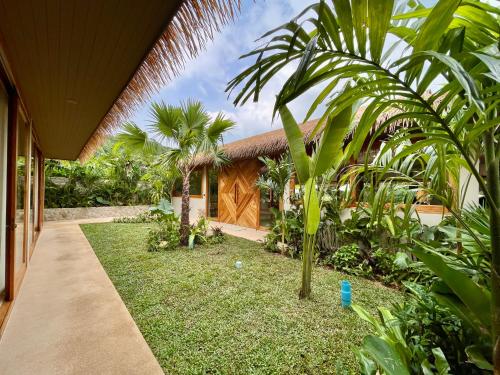 a house with a garden with palm trees and a walkway at Wild Cottages Elephant Sanctuary Resort in Amphoe Koh Samui