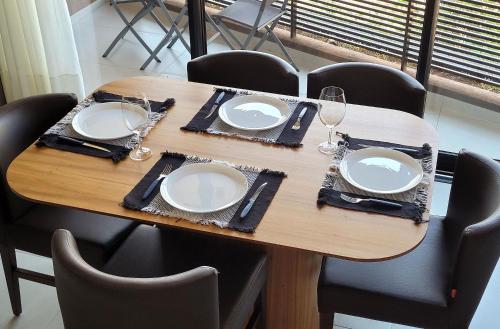 a wooden table with plates and wine glasses on it at Blend Coliving One - 1 in Ribeirão Preto
