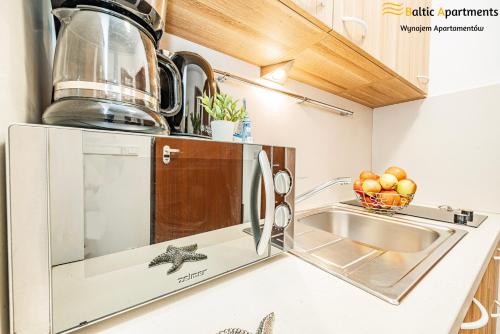 a kitchen with a sink and a microwave at Baltic Apartments - Apartamenty Aquamarina in Świnoujście