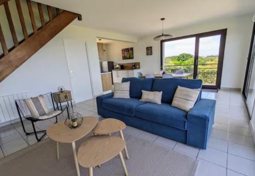 un salon avec un canapé bleu et une table dans l'établissement La marée basse - vue mer imprenable, à Saint-Pol-de-Léon