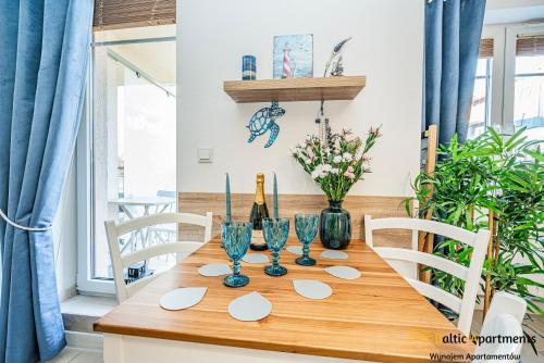 a dining room table with wine glasses and flowers at Baltic Apartments - Apartamenty Aquamarina in Świnoujście