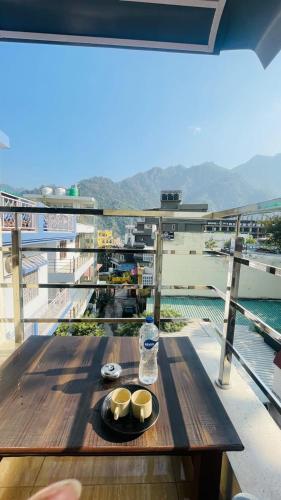 a table with a bottle of water and bowls on a balcony at The Gange Hill By Green Bird Hospitality in Rishīkesh