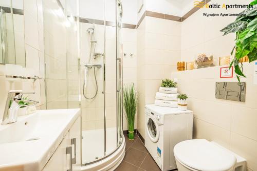 a bathroom with a shower toilet and a washing machine at Baltic Apartments - Apartamenty Aquamarina in Świnoujście
