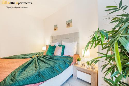 a bedroom with a bed with green sheets and a plant at Baltic Apartments - Apartamenty Aquamarina in Świnoujście